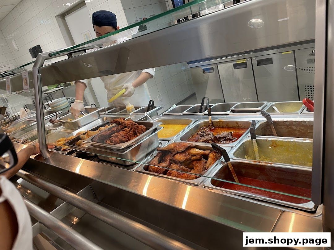A food service counter with various dishes and a staff member serving.