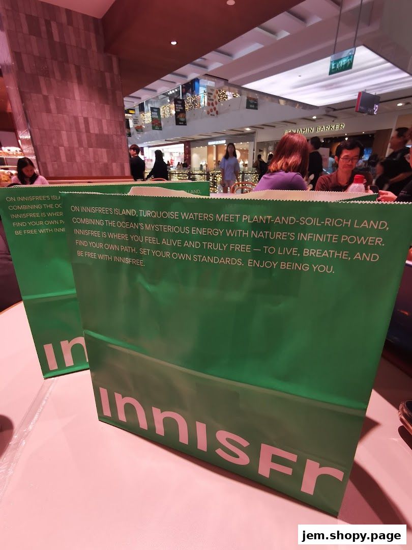 Green shopping bags from Innisfree with brand messaging are displayed on a table.