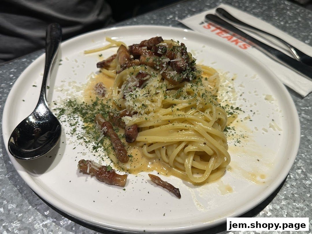 A plate of spaghetti carbonara with bacon and grated cheese, served with a spoon.