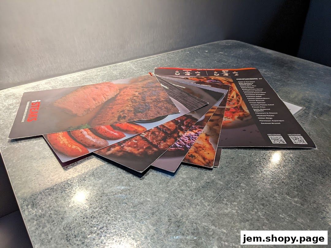 A stack of menus from iSTEAKS Jem featuring images of steaks and sausages.