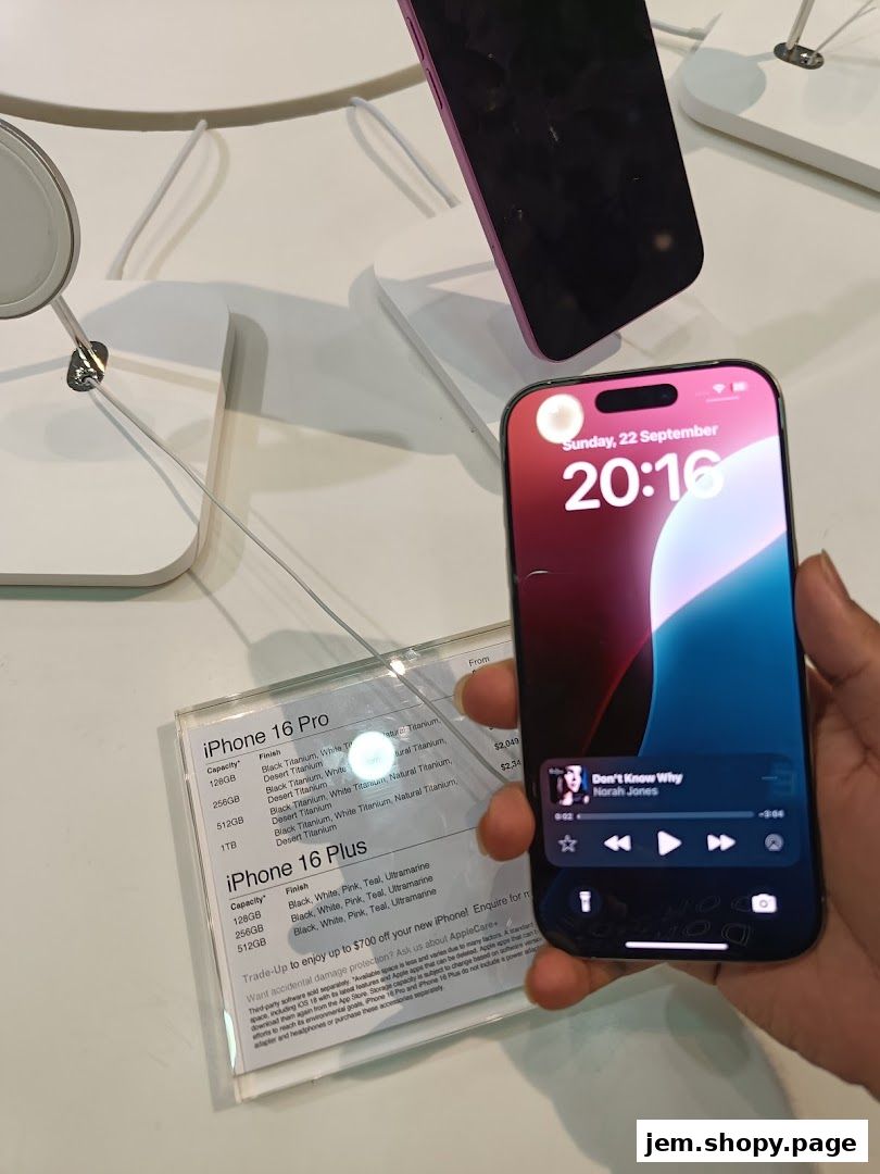 A hand holds an iPhone displaying music, next to a display of iPhone models and pricing.