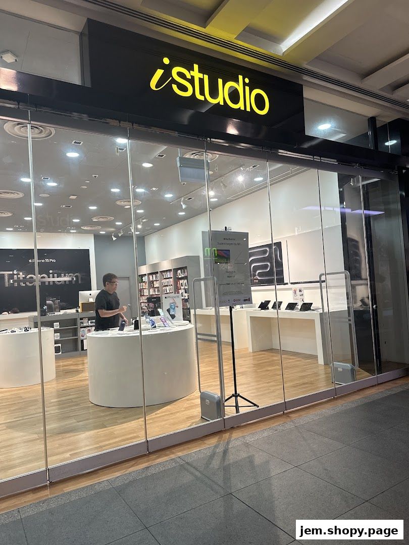 The exterior of an iStudio shop, showcasing Apple products and a staff member.