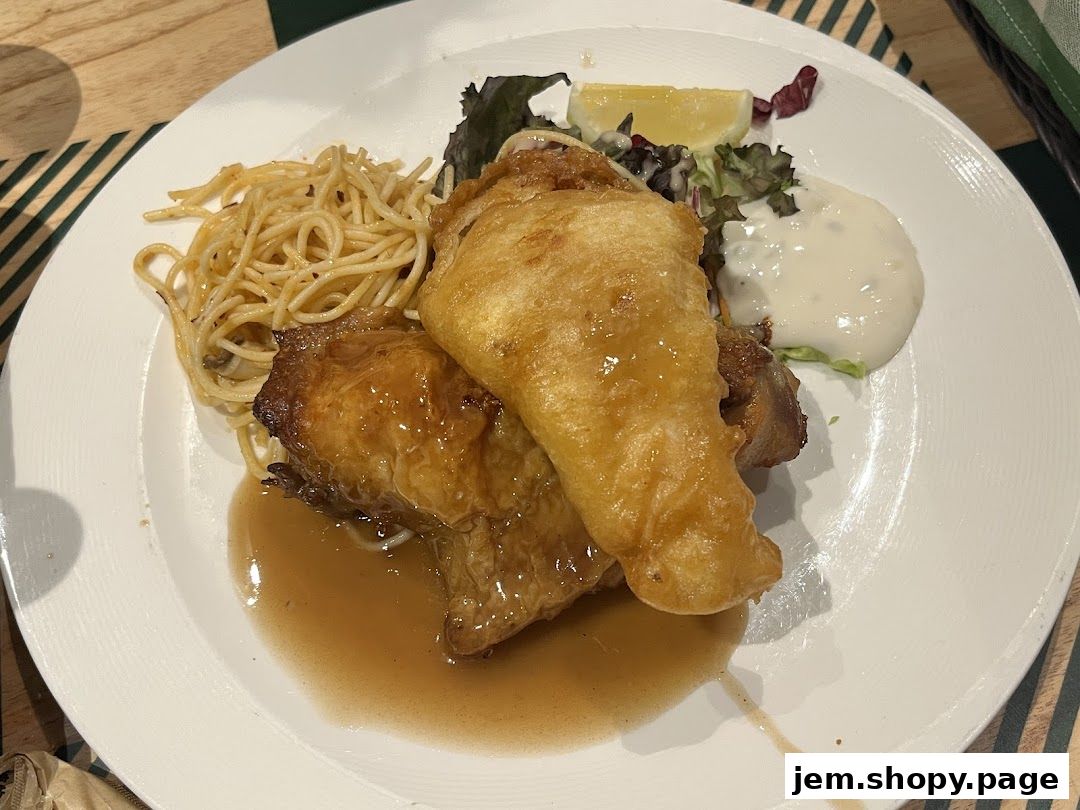 A plate of food featuring fried chicken, spaghetti, salad, and sauce.