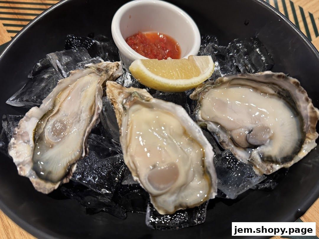 Fresh oysters served on ice with a lemon wedge and dipping sauce.