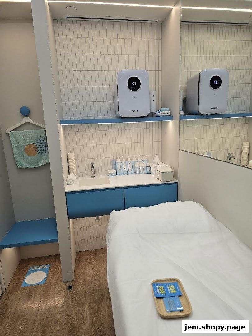 Interior of a clean, modern beauty treatment room with a bed and sink.