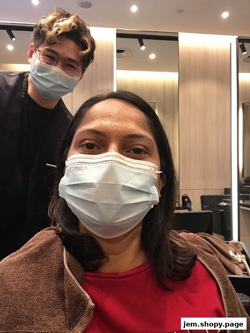 A hairstylist and a client wearing face masks in a salon.