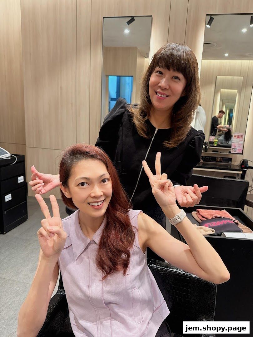 Two women smiling and making peace signs inside a modern hair salon.