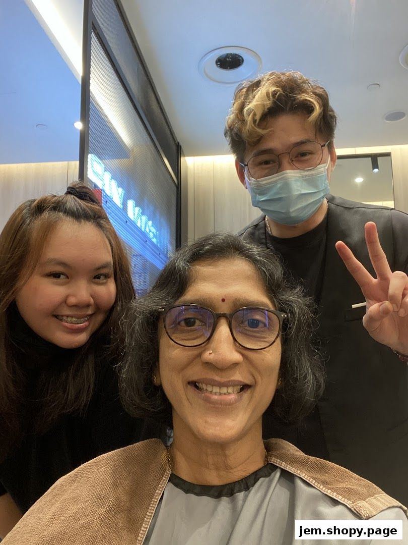Three smiling people, two customers and a stylist, pose for a selfie in a salon.