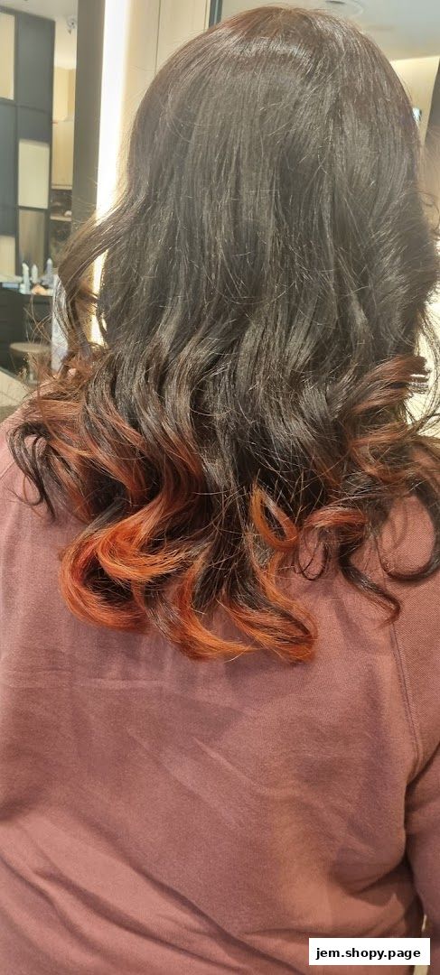 A person's dark hair with subtle orange highlights and curls.