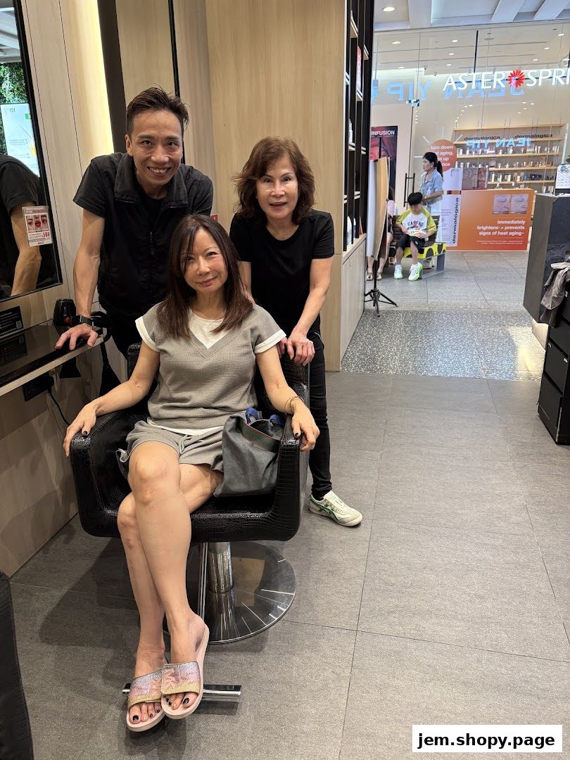 A woman sits in a salon chair with two stylists behind her.