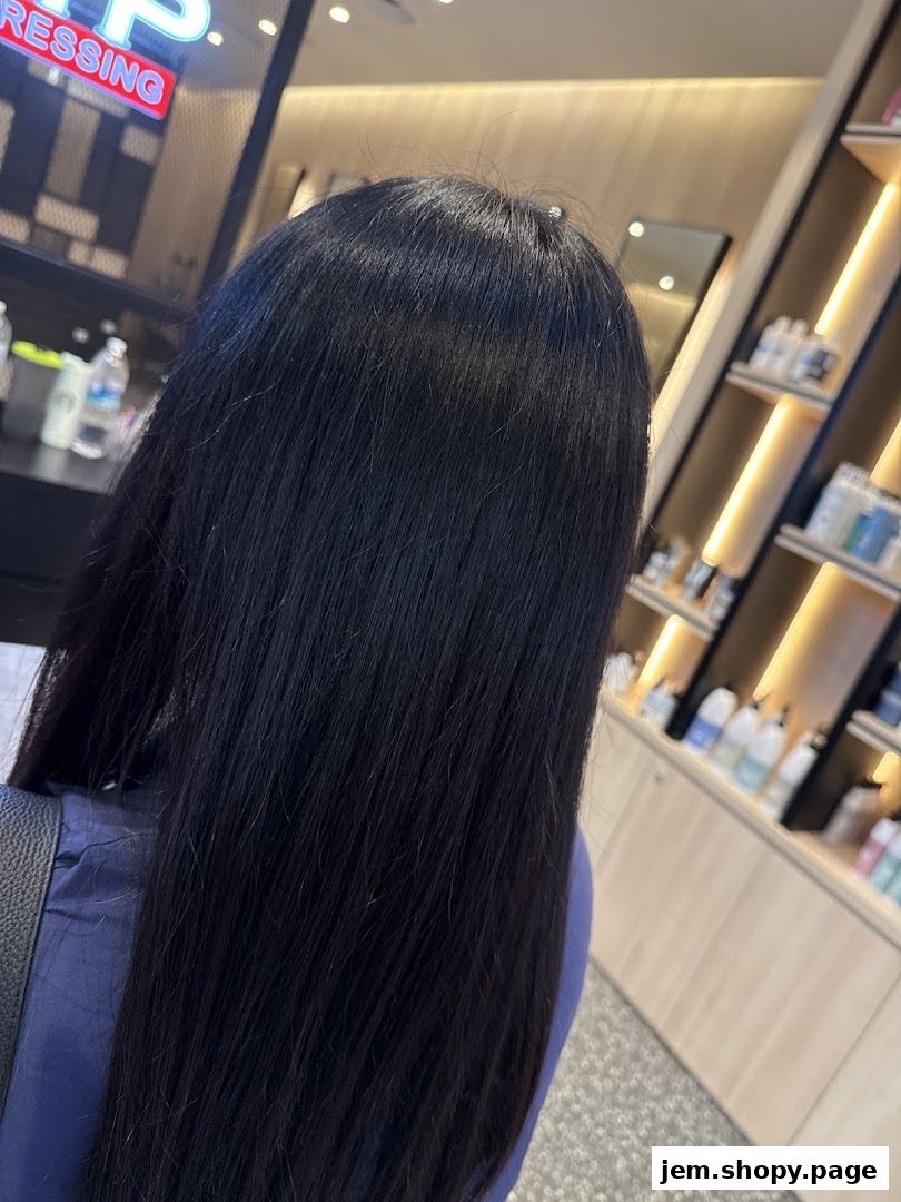 A person with long, dark hair inside a modern hair salon.