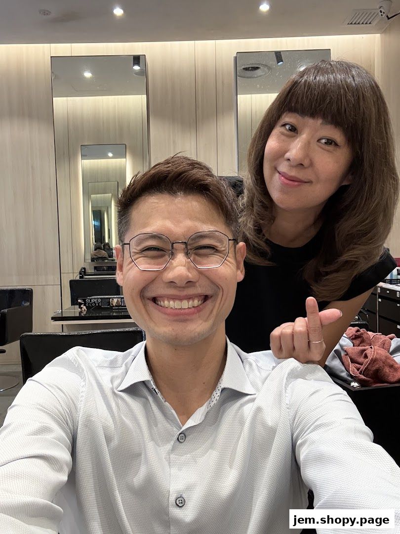 A smiling man and a woman posing for a selfie in a modern hair salon.