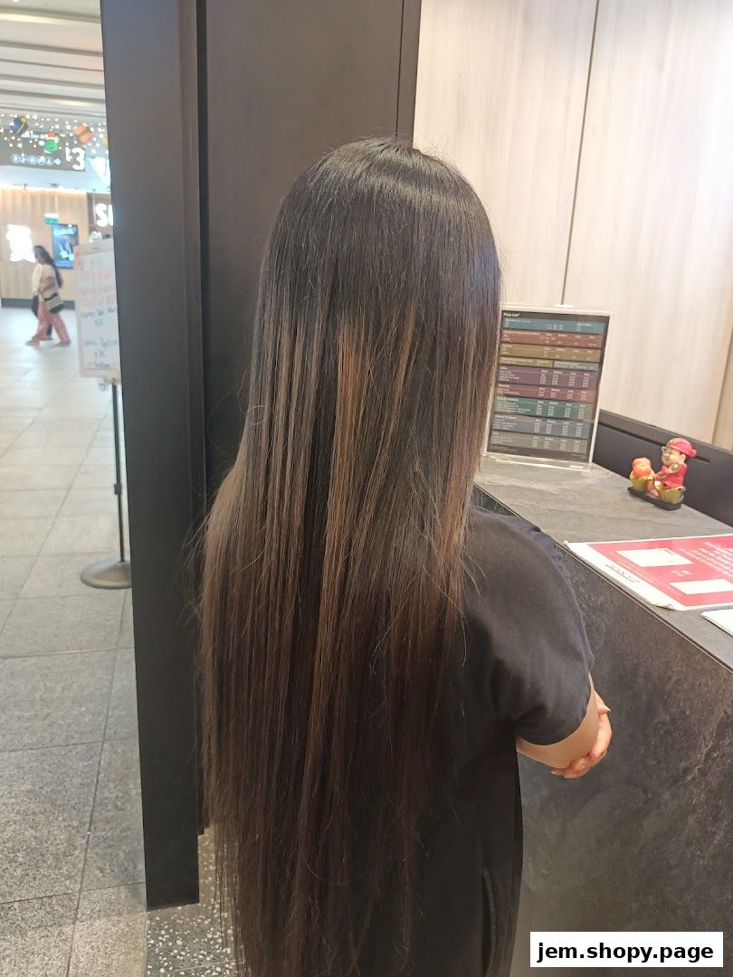 A person with long, dark hair stands near a reception desk with a price list.