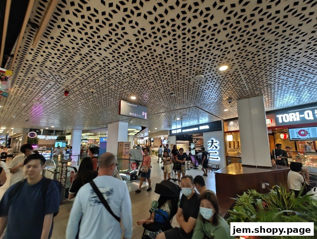 People walking through a mall with shops and decorative ceiling.