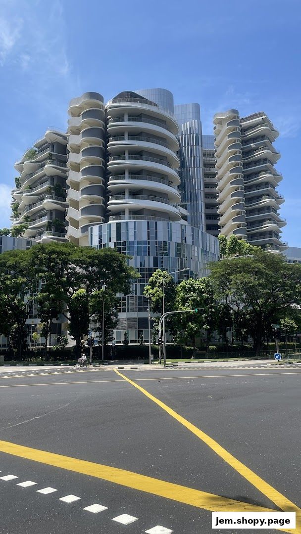 A modern architectural building with curved balconies and glass facade under a clear blue sky.