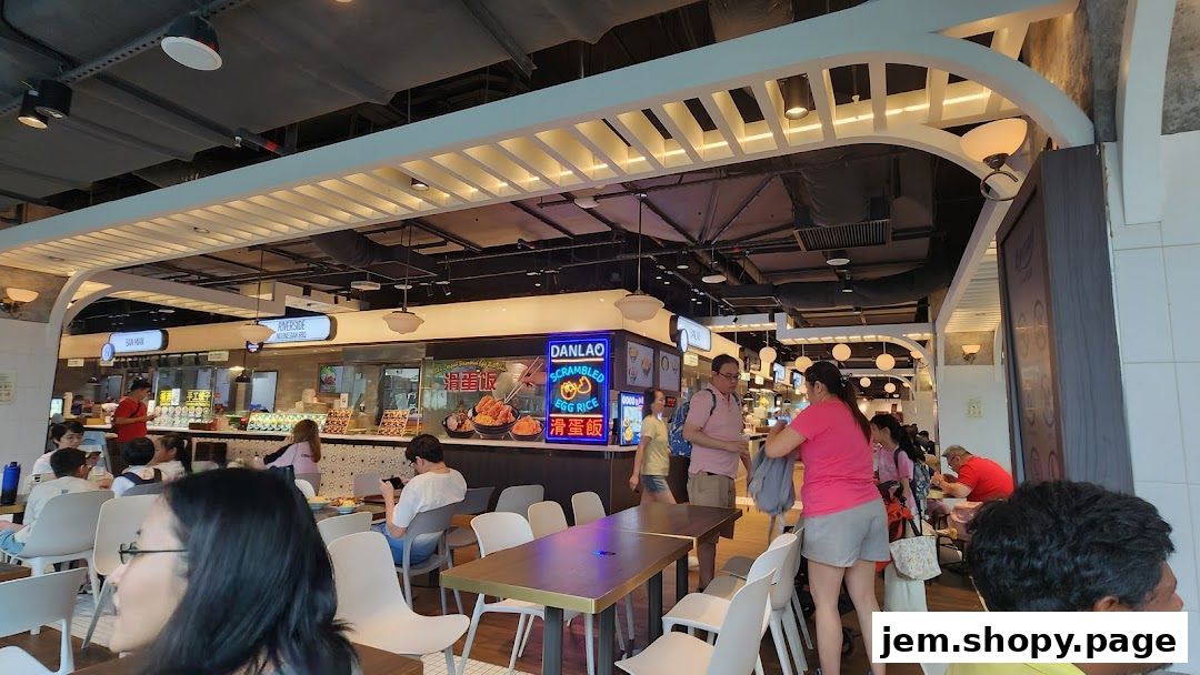 A busy food court with various stalls and diners enjoying their meals.