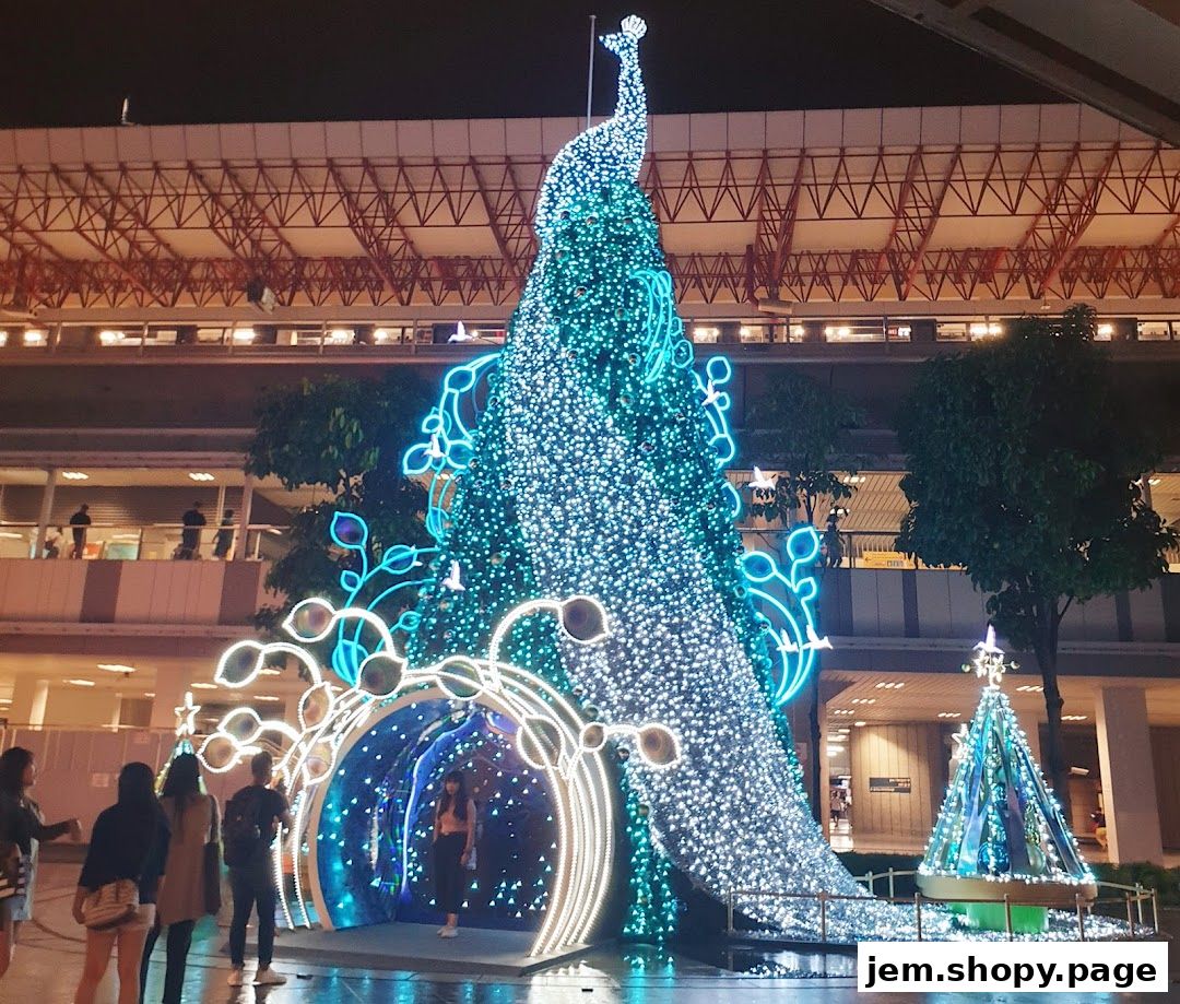 A large, illuminated Christmas tree shaped like a peacock at night.