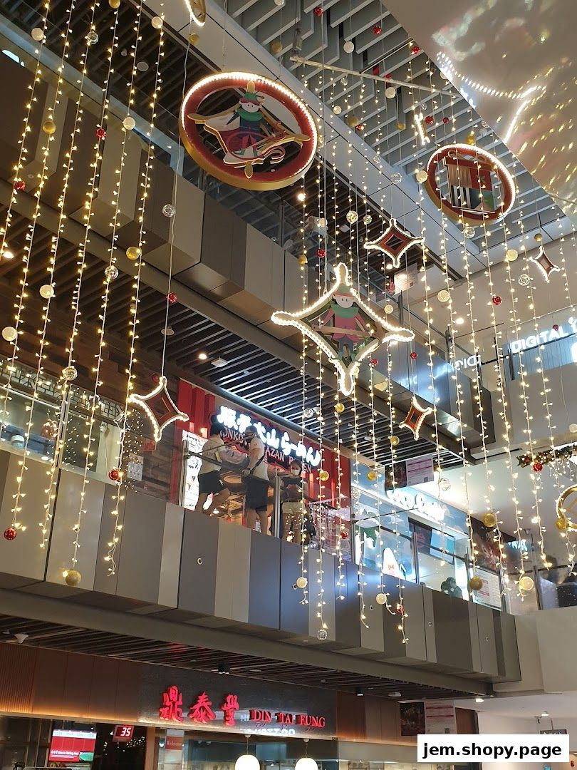 Festive Christmas decorations with lights and ornaments adorn a shopping mall interior.