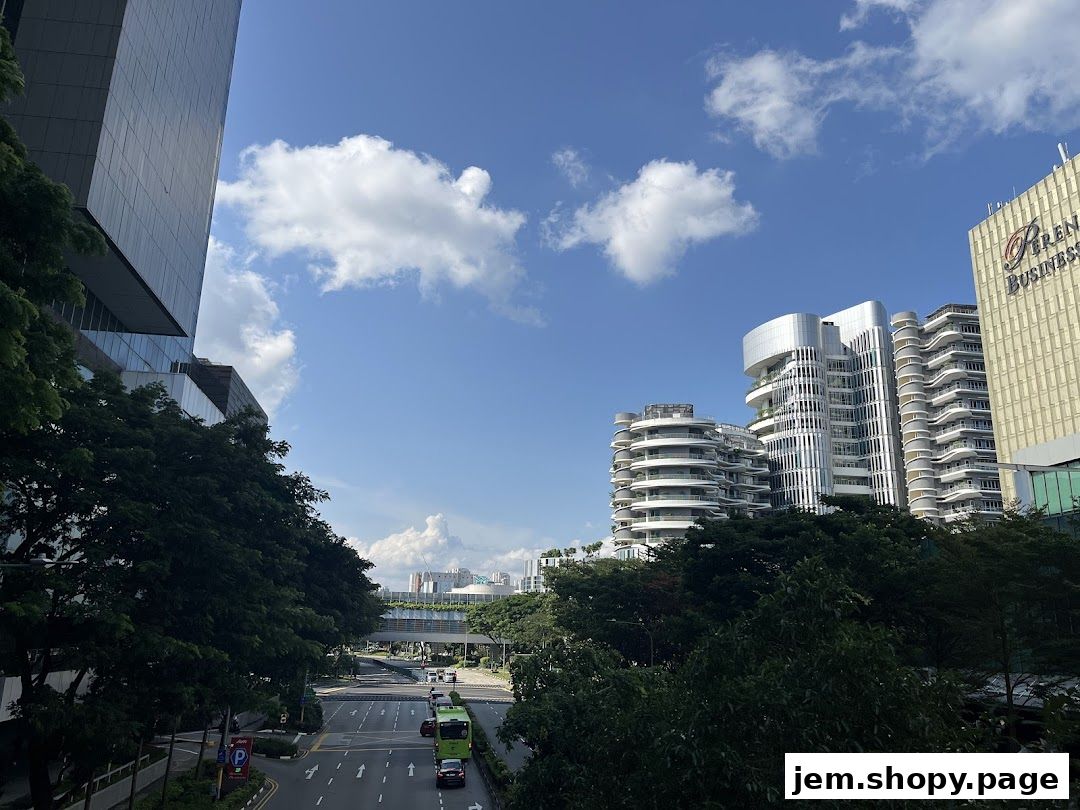 Modern buildings and a street scene under a bright blue sky with scattered clouds.