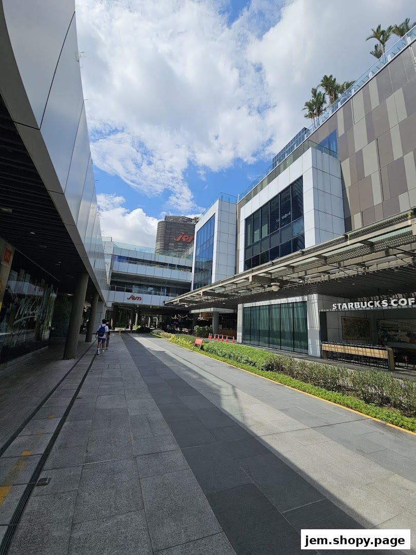 A modern shopping mall walkway with shops like Jem and Starbucks Coffee visible.