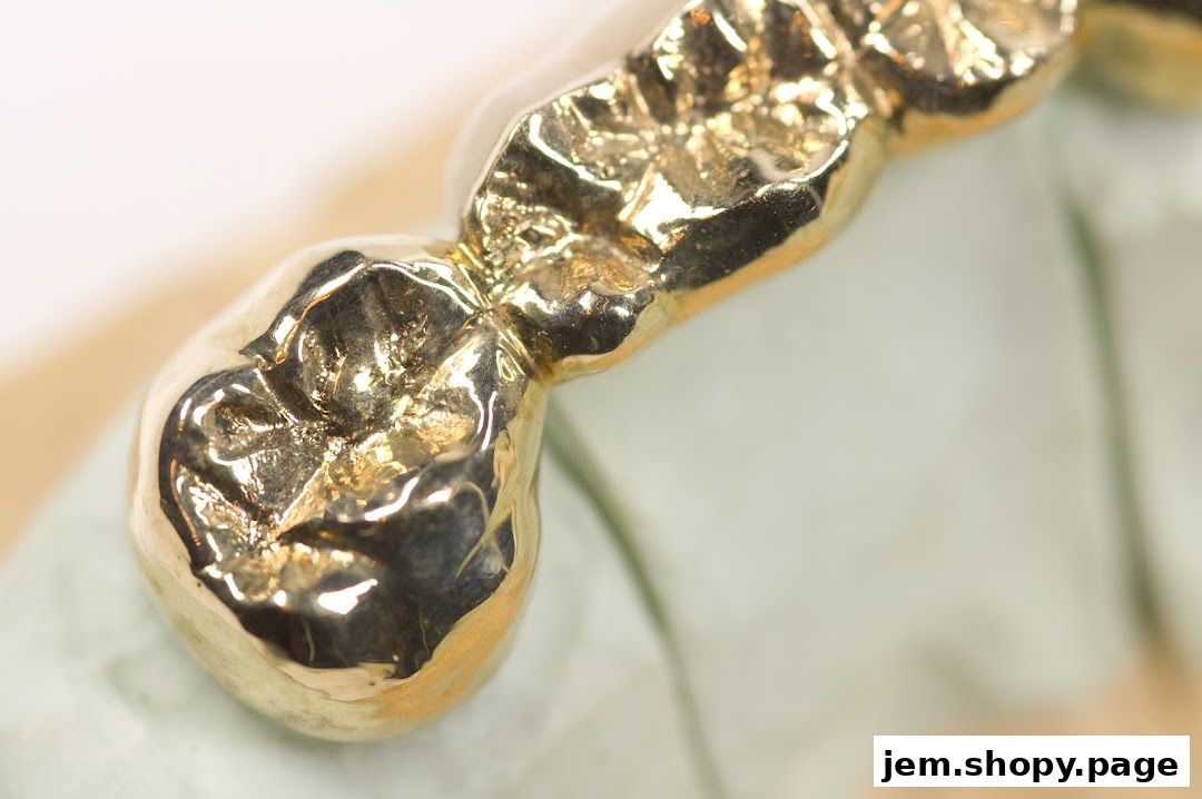 Close-up of a gold dental crown on a light green dental model.