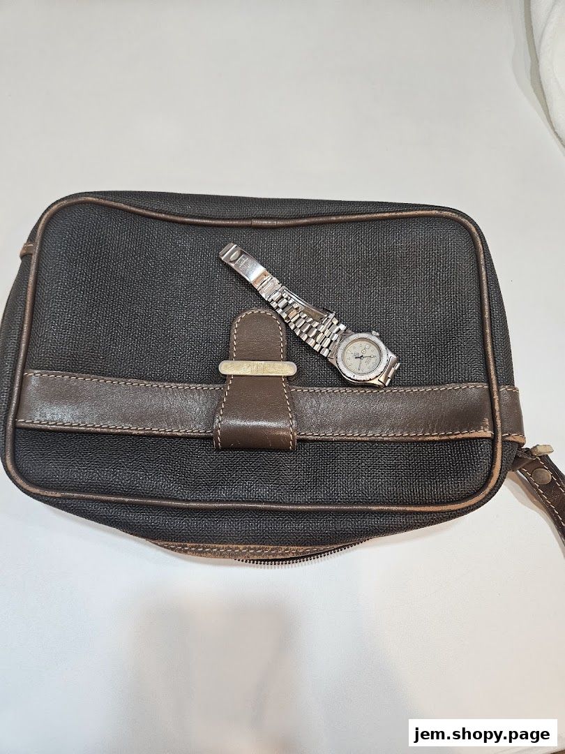 A dark brown textured pouch with a leather strap and a silver watch on top.