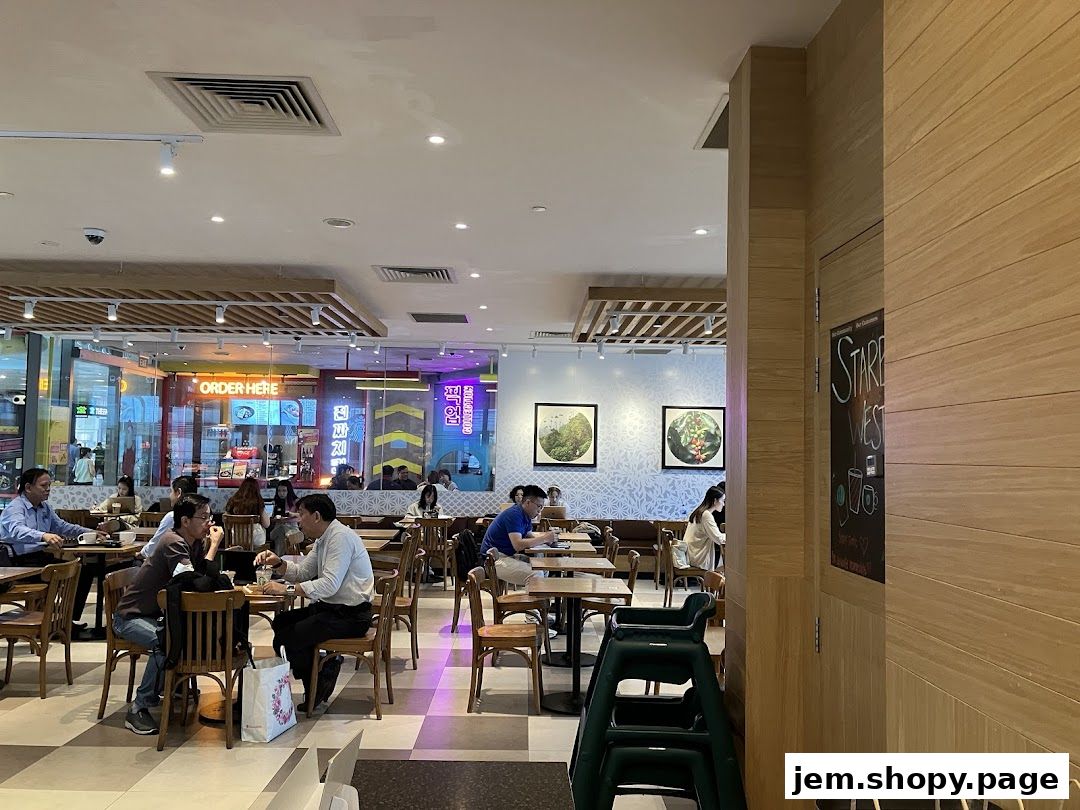 Interior view of a busy cafe with customers seated at tables and a counter in the background.