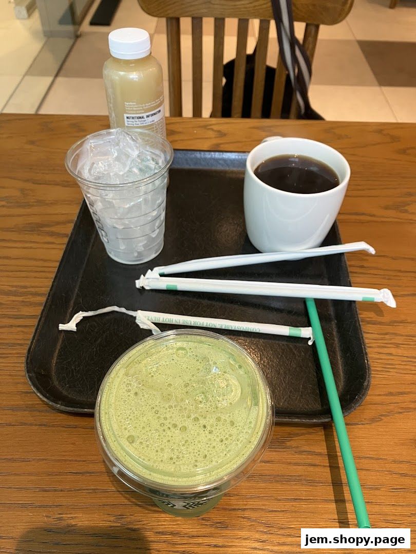 A tray with a coffee, iced drink, bottled beverage, and straws on a wooden table.