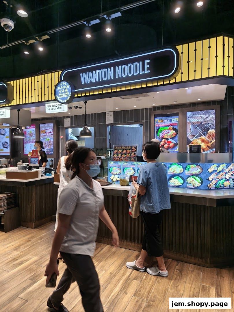 A food stall named Kallang Airport Wanton Noodle with a prominent sign and display of food.