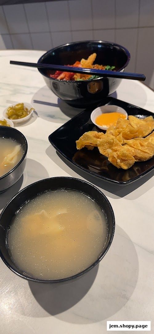 A close-up of a delicious meal featuring noodles, wontons, and soup.