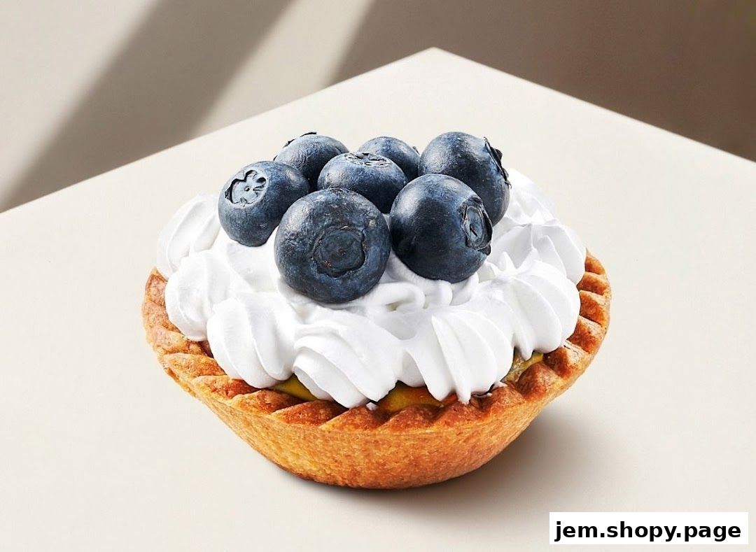 A close-up of a delicious blueberry tart topped with whipped cream and fresh blueberries.