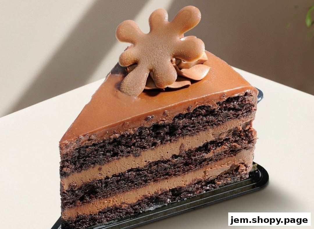 A decadent slice of multi-layered chocolate cake with rich frosting and a chocolate decoration.