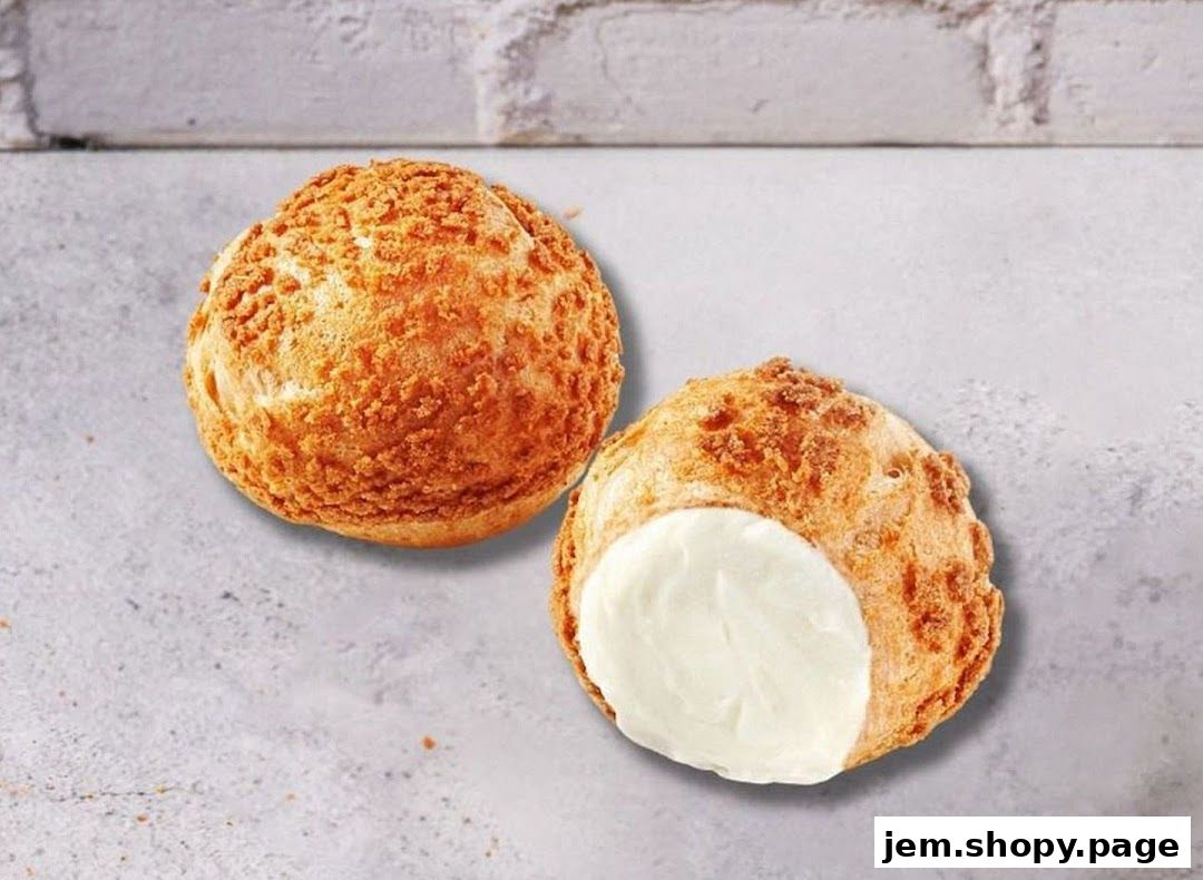 Two cream puffs, one filled with white cream, on a textured surface.