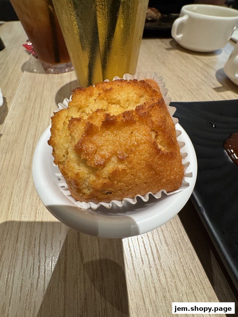 A close-up of a golden-brown muffin served in a white ramekin on a wooden table.