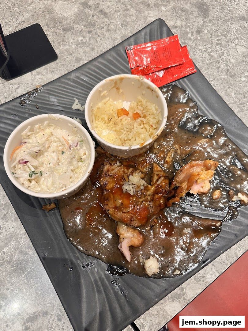 A plate of Kenny Rogers Roasters chicken with rice and coleslaw, partially eaten.