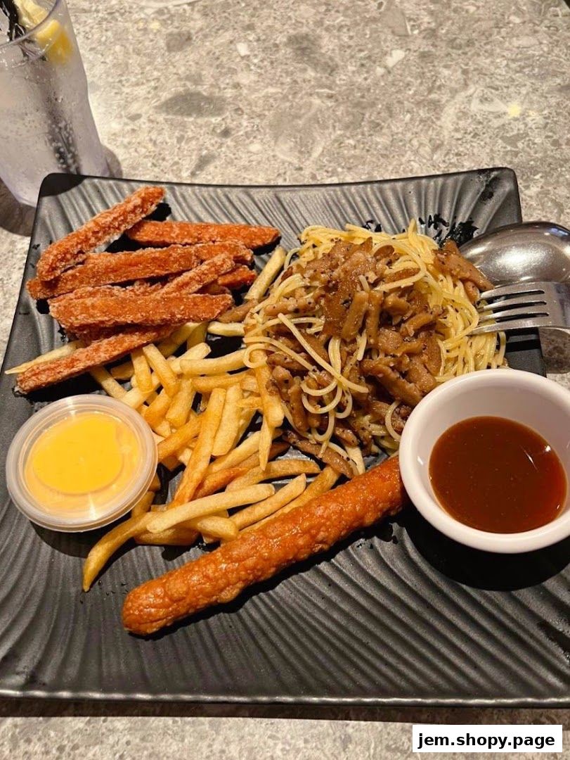 A plate of Kenny Rogers Roasters meal with fried chicken strips, fries, pasta, and a sausage.