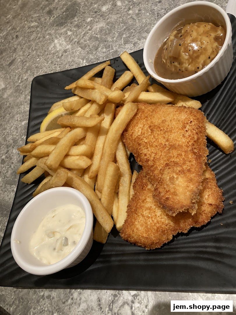 A plate of crispy fish and chips with mashed potatoes and tartar sauce.
