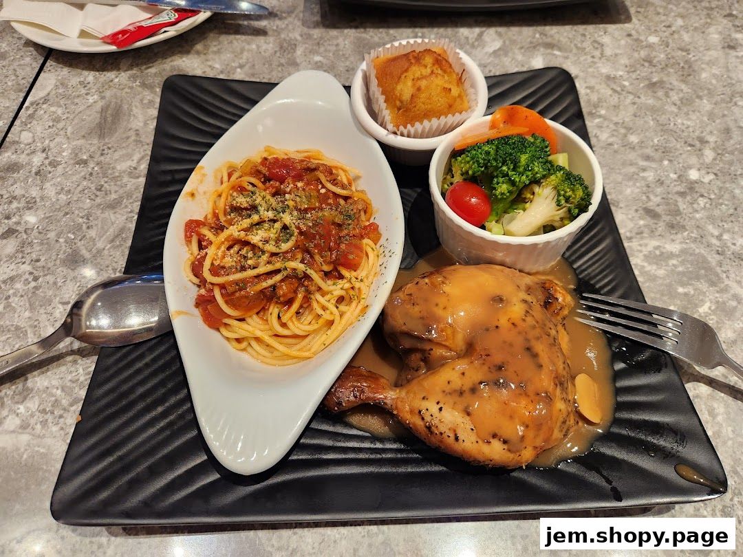 A delicious meal featuring roasted chicken, spaghetti, a muffin, and a side of vegetables.