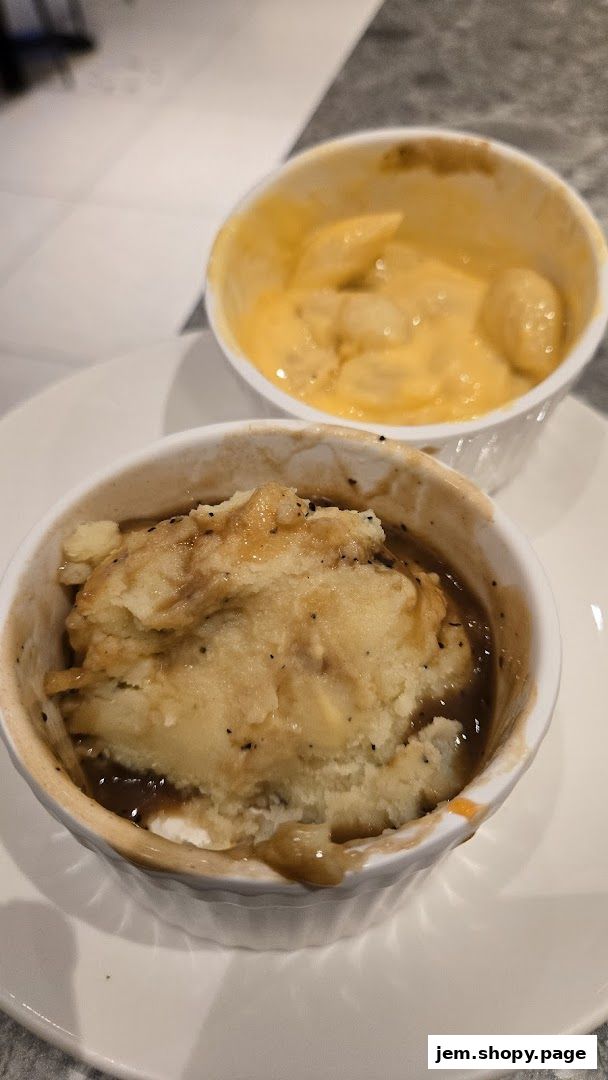 Two small ramekins of food, one with mashed potatoes and gravy, the other with mac and cheese.