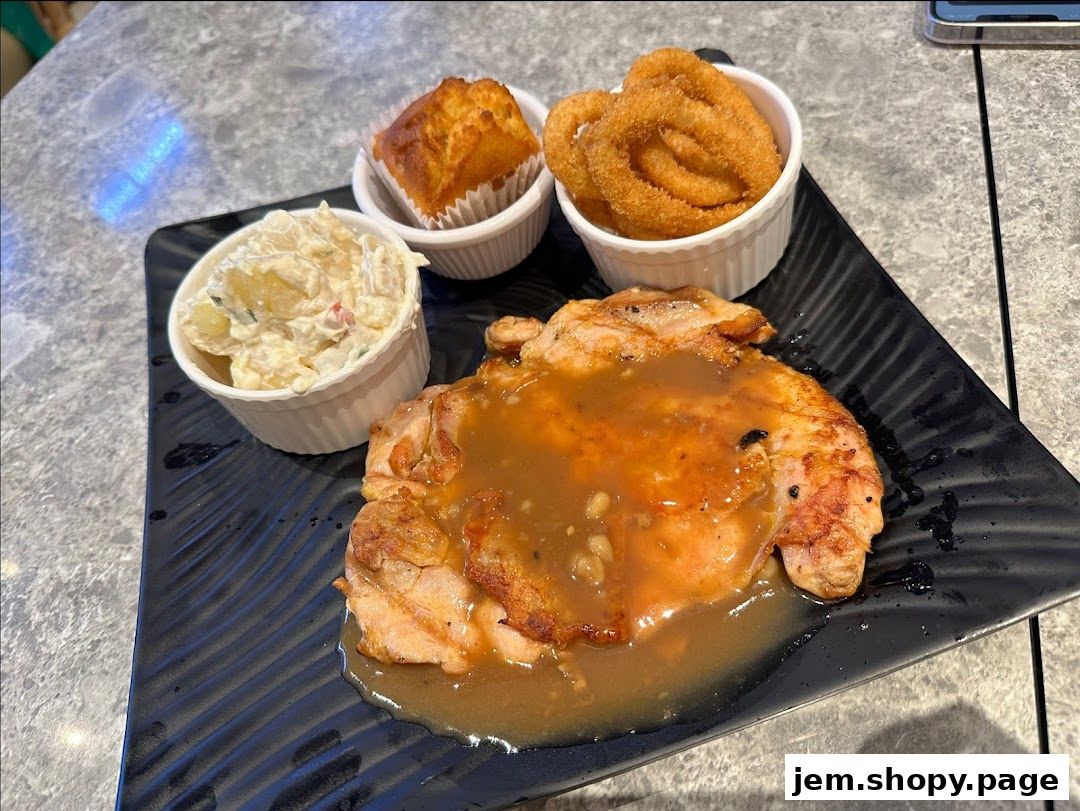 A plate of Kenny Rogers Roasters chicken with sides of coleslaw, onion rings, and a muffin.