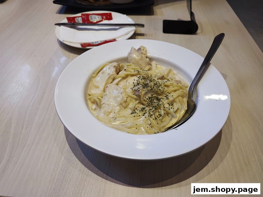 A creamy pasta dish with chicken and herbs served in a white bowl with a spoon.