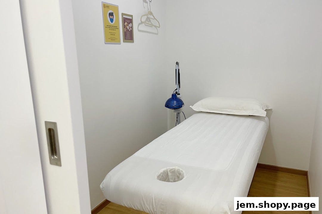 A clean treatment room with a massage bed and therapeutic lamp.