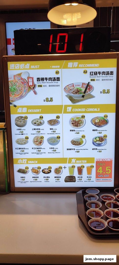 A menu board displaying various noodle soups, dumplings, rice dishes, snacks, and drinks with prices.