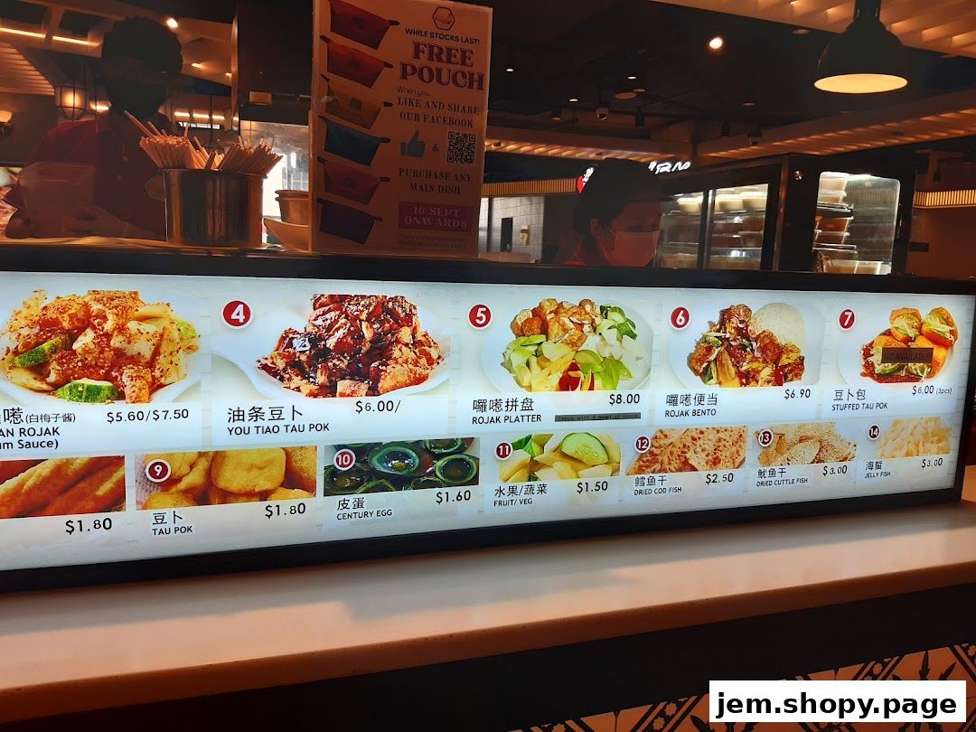 A digital menu board displaying various food items with images and prices at Kopitiam Food Hall.