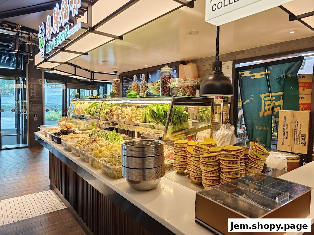 A food counter displaying fresh ingredients and stacked bowls at Kopitiam Food Hall.