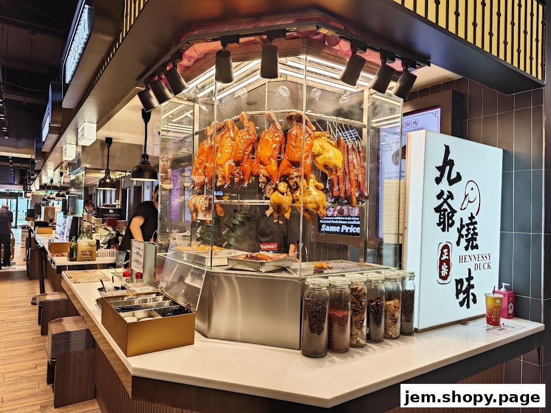 A food stall displaying roasted ducks and other meats, with jars of spices and a menu board.