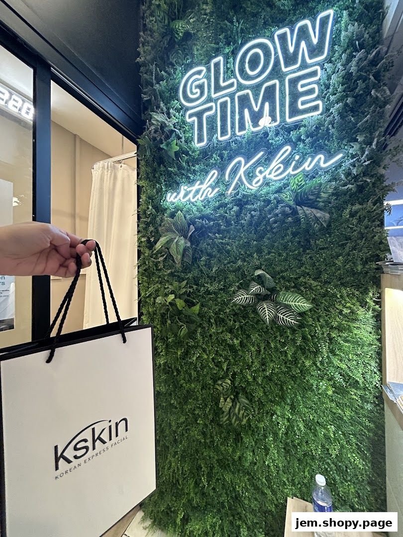 A hand holds a Kskin shopping bag in front of a green wall with a neon sign.