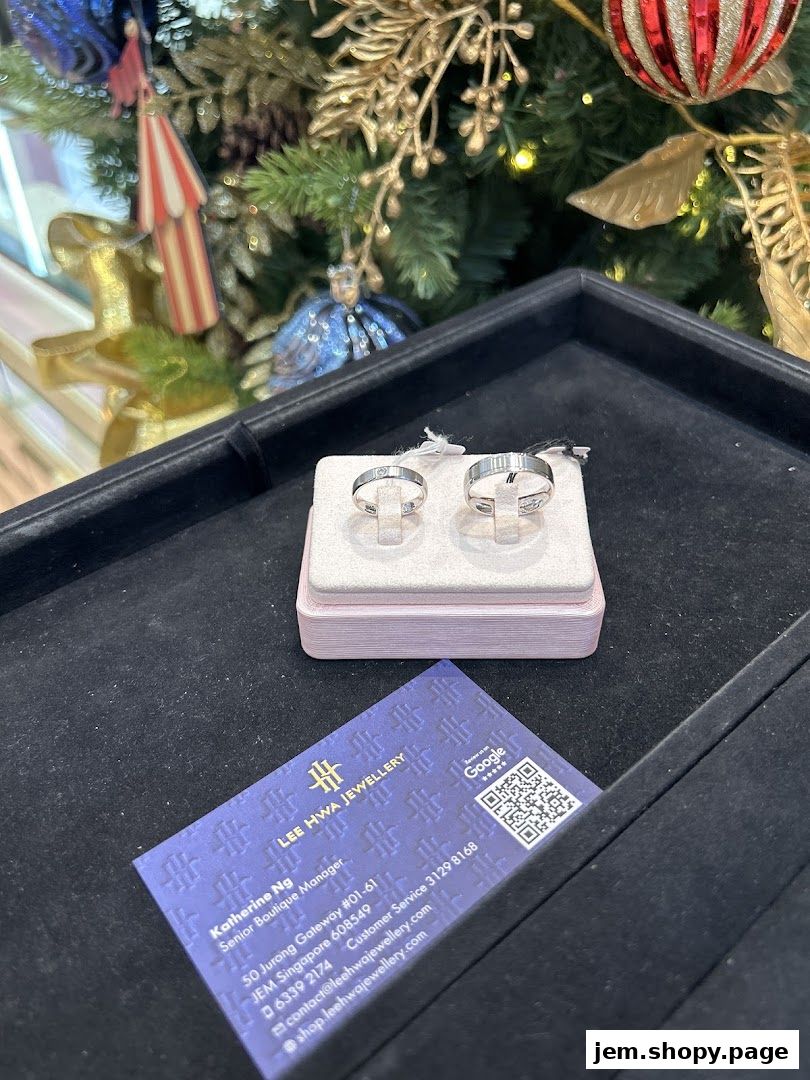 Two elegant rings displayed on a stand with a business card and festive decorations.