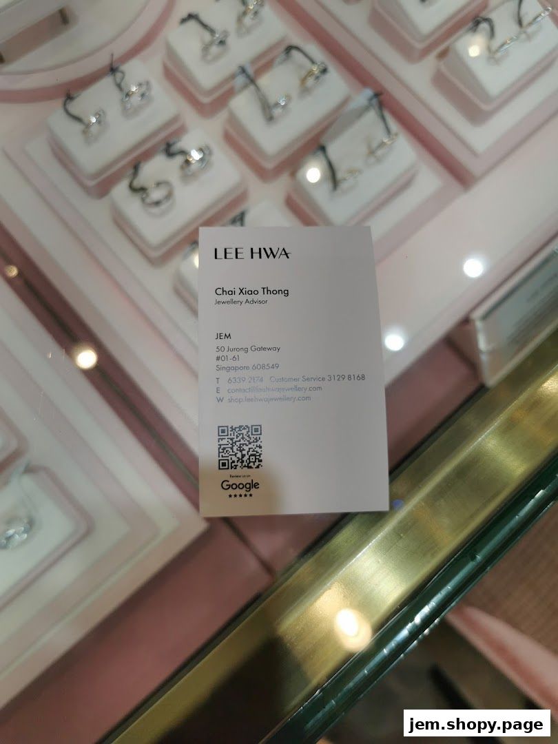 A business card for a Jewellery Advisor at Lee Hwa Jewellery, displayed among jewelry.