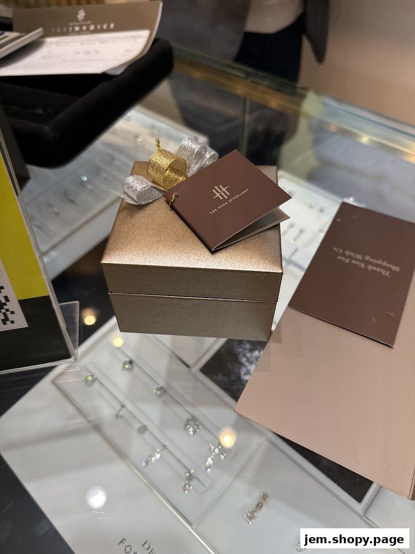 A gift box from Lee Hwa Jewellery with a tag and ribbon, displayed on a counter.